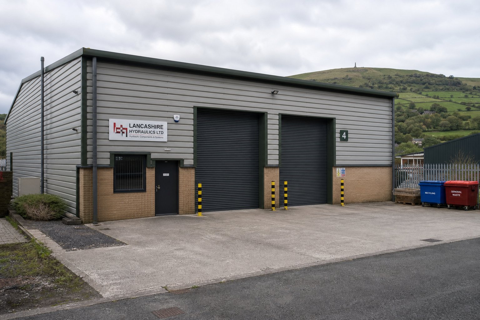 Commercial Mortgages In Haslingden 12 Light industrial commercial property with roller doors and hillside backdrop near Haslingden.